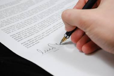 Person unterschreibt Vertrag mit rechter Hand mit einem Füller.