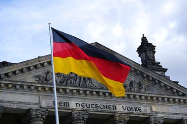 Deutschland-Fahne (Schwarz, Rot, Gold) an Fahnenmast vor dem Reichtstagsgebäude in Berlin.